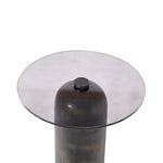 Round glass table with a dark metal base on a white background