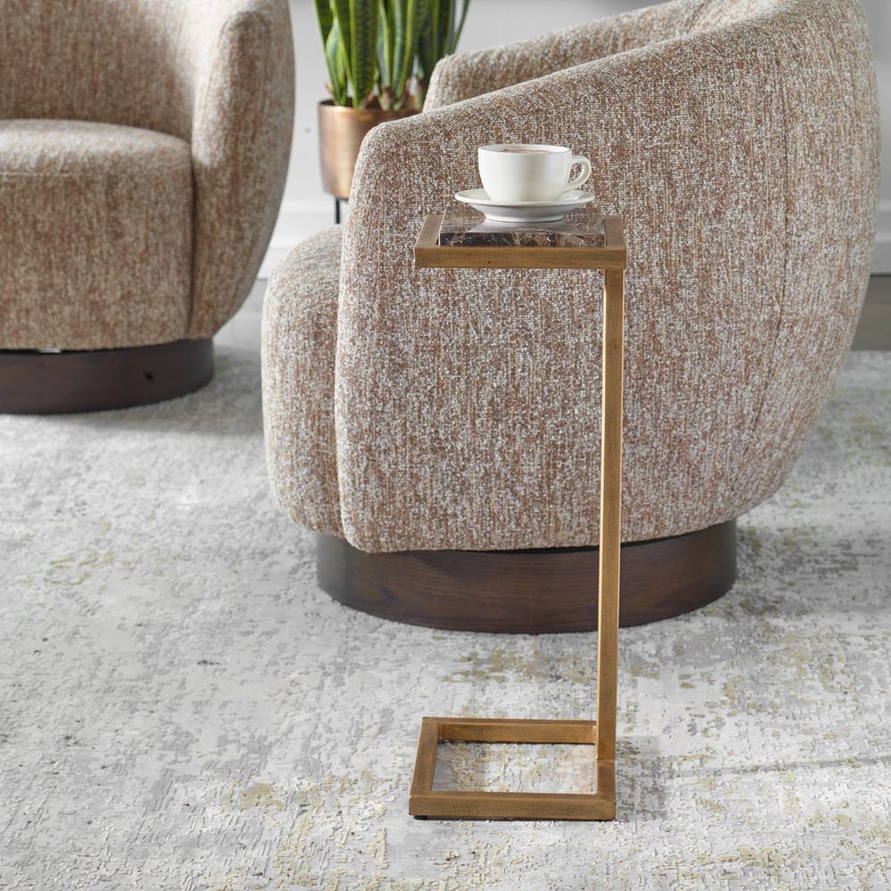 Beige armchair with a small wooden side table and a cup on a light gray carpet.