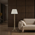 Modern living room with a beige sofa and floor lamp against a dark paneled wall.
