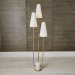 Set of three floor lamps with white shades against a wooden paneled wall.