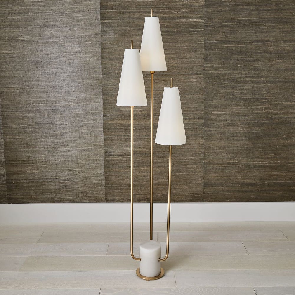 Set of three floor lamps with white shades against a wooden paneled wall.