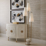 Decorative cabinet with two framed abstract artworks, two floor lamps, and a small candle on a neutral wall.