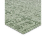 A rectangular, solid green area rug with a textured design.