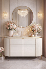 Luxurious interior with a white dresser, round mirror, and floral arrangements.