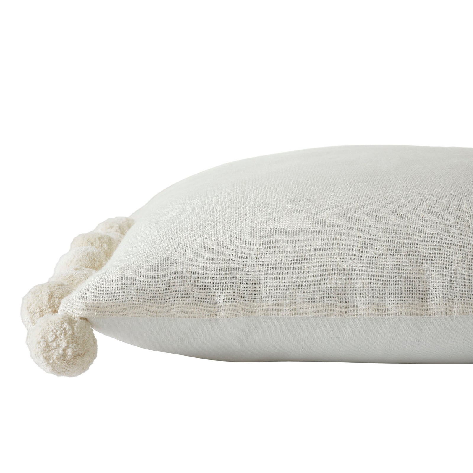 A square-shaped decorative pillow with solid pattern and pom pom detailing on the edges, primarily in a natural white color.