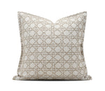 A square throw pillow with a beige geometric lattice pattern on a white textured fabric, shown against a plain white background with a brand watermark at the bottom.