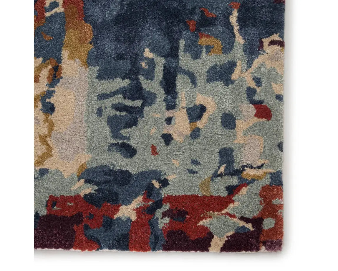 A rectangular area rug featuring a geometric pattern with a mix of blue, red, and beige colors.
