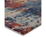 A rectangular area rug featuring a geometric pattern with a mix of blue, red, and beige colors.