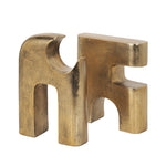 Gold metal sculpture of interlocking shapes on a white background