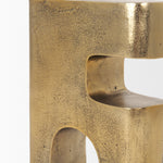 Gold metal sculpture of interlocking shapes on a white background