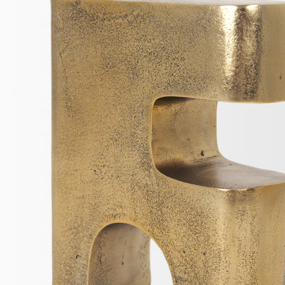 Gold metal sculpture of interlocking shapes on a white background