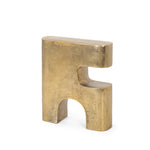 Gold metal sculpture of interlocking shapes on a white background