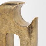 Gold metal sculpture of interlocking shapes on a white background