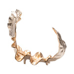 A decorative gold leaf object with a wavy and textured design, predominantly gold in color with some silver accents.