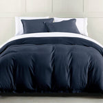 Dark blue bedding set on a bed with white pillows against a neutral wall.