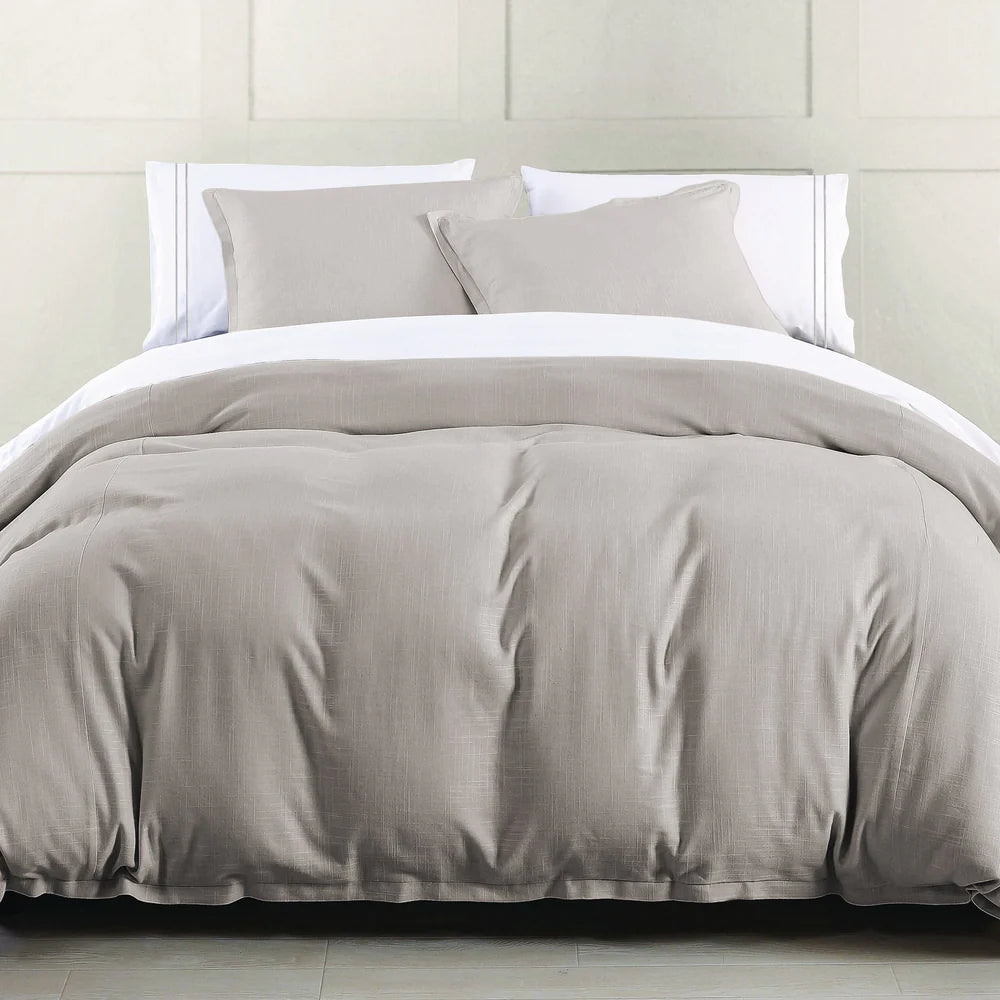 Gray comforter set on a bed with white pillows against a light gray wall.