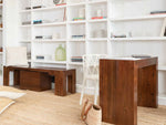 Wooden desk and chairs in a room with white bookshelves.