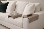 Sofa with wooden side tables holding a cup and remote control.