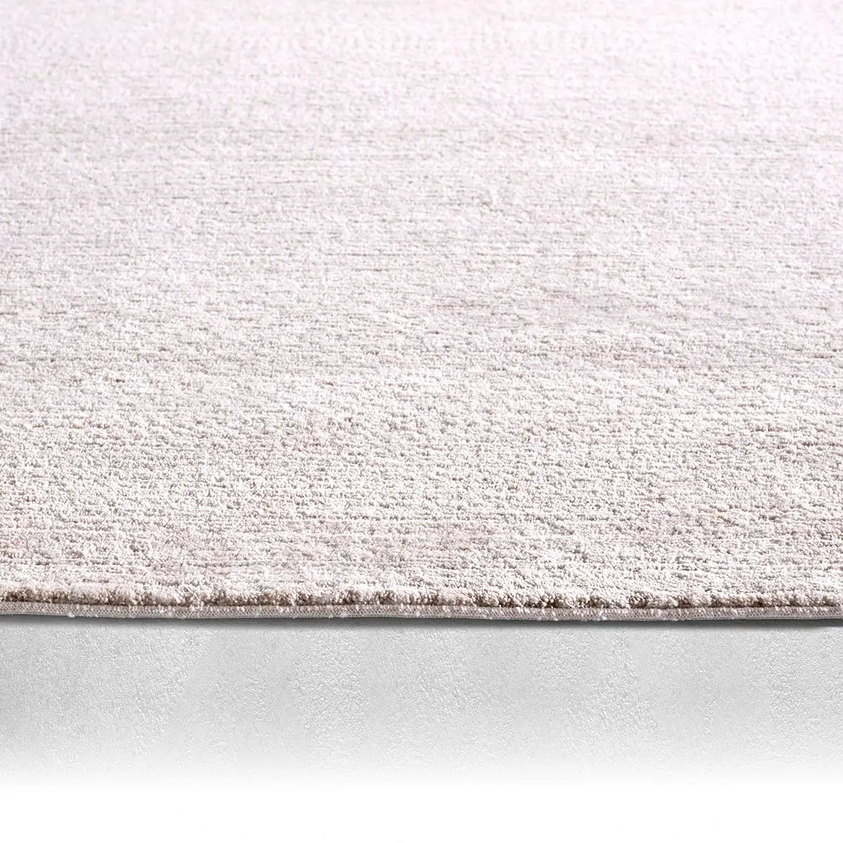 Close-up of a textured rug with a gradient color transition from beige to gray.