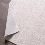 Close-up of a textured white rug on a wooden floor