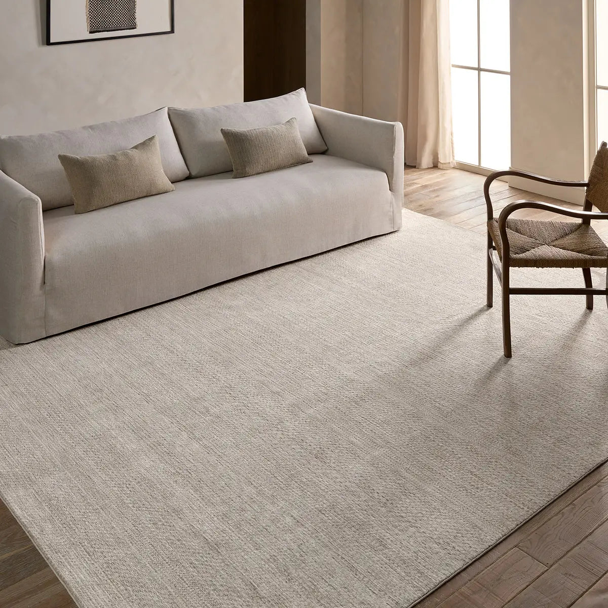 Beige sofa and chair in a room with a large beige rug.