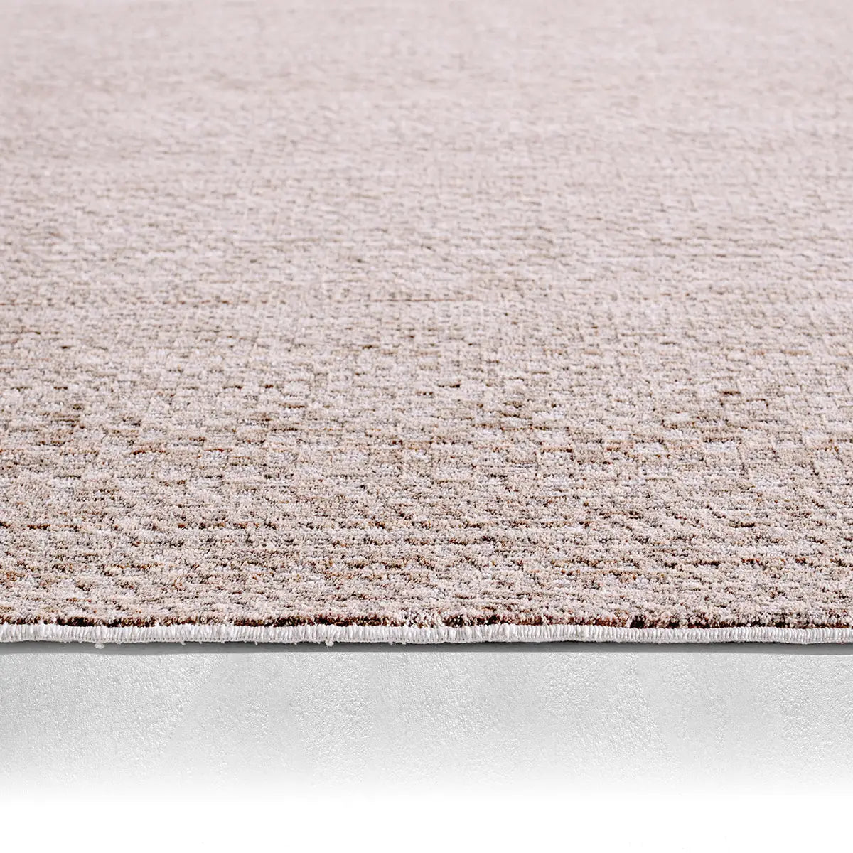 Close-up of a textured beige carpet border on a light gray background
