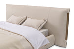 Beige upholstered bed with white bedding on a white background