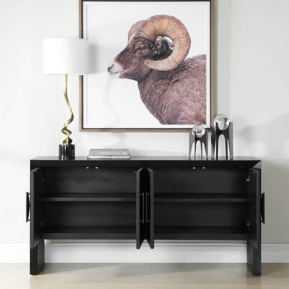 Black console table with decorative items and a framed animal print on a white wall.