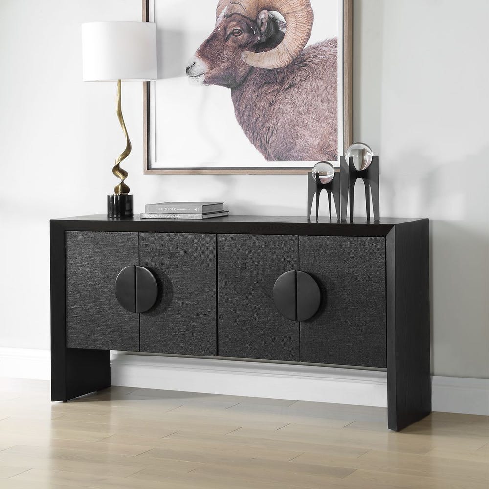 Black sideboard with decorative items in a room with a wall art of a ram.