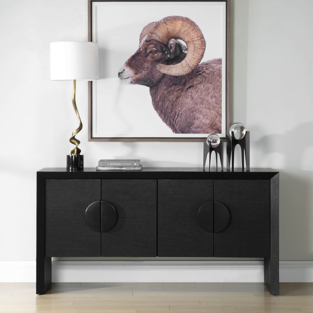 Black cabinet with decorative items and a framed picture of a ram on a white wall.