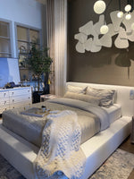 A white slipcover on a bed within a bedroom setting, with pillows and a quilt.