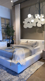 A white slipcover on a bed within a bedroom setting, with pillows and a quilt.