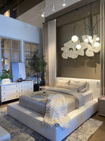A white slipcover on a bed within a bedroom setting, with pillows and a quilt.