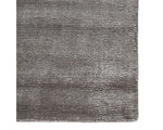 A dark gray area rug with a textured weave, handwoven from a blend of wool and viscose.