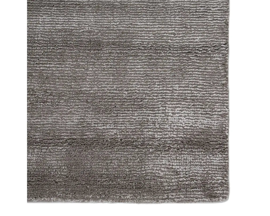 A dark gray area rug with a textured weave, handwoven from a blend of wool and viscose.
