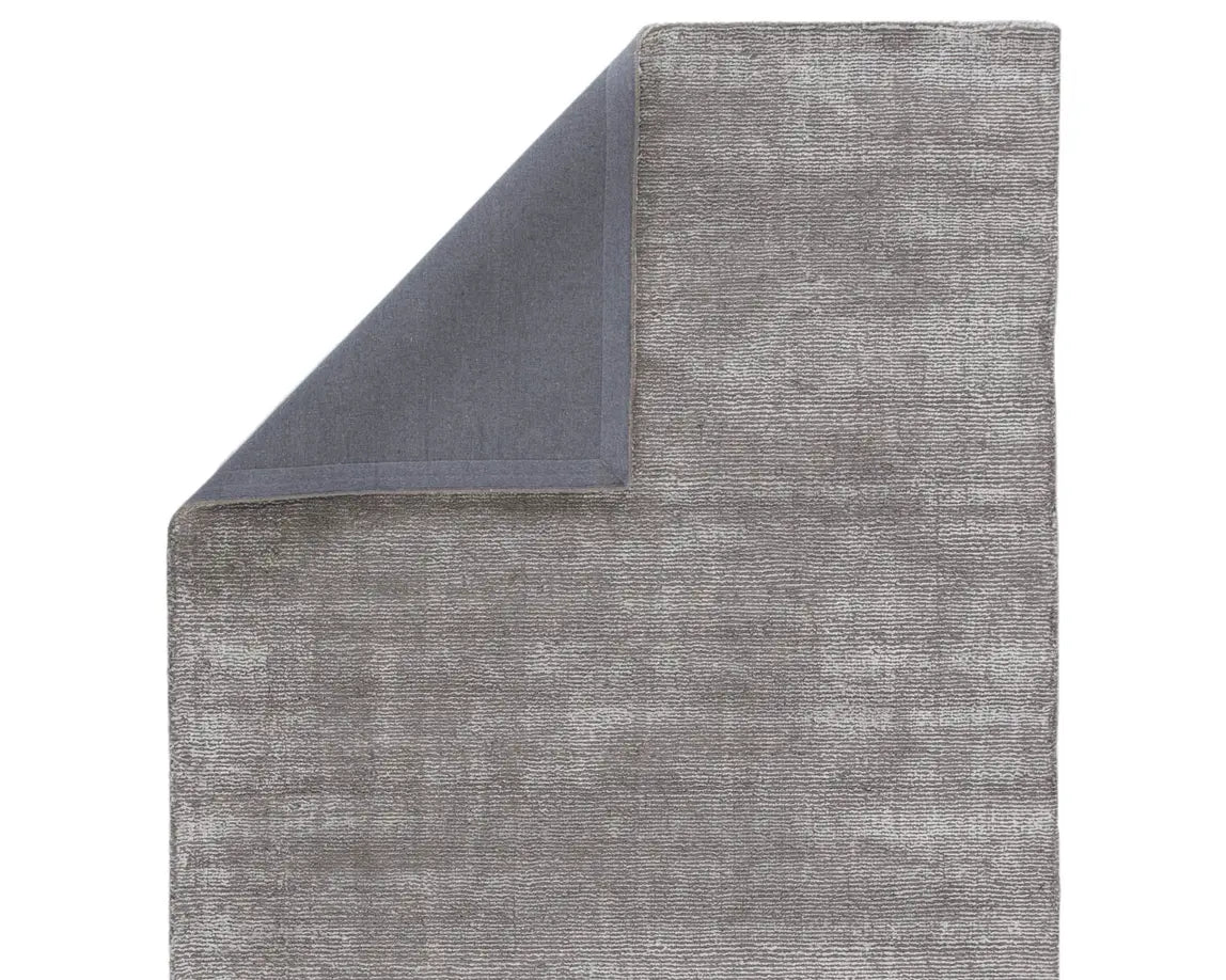 A dark gray area rug with a textured weave, handwoven from a blend of wool and viscose.