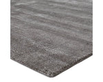 A dark gray area rug with a textured weave, handwoven from a blend of wool and viscose.