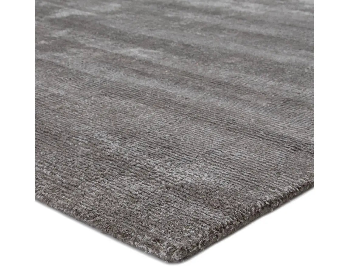 A dark gray area rug with a textured weave, handwoven from a blend of wool and viscose.