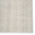 An ivory-colored area rug with a textured weave, partially showing its thickness and material.