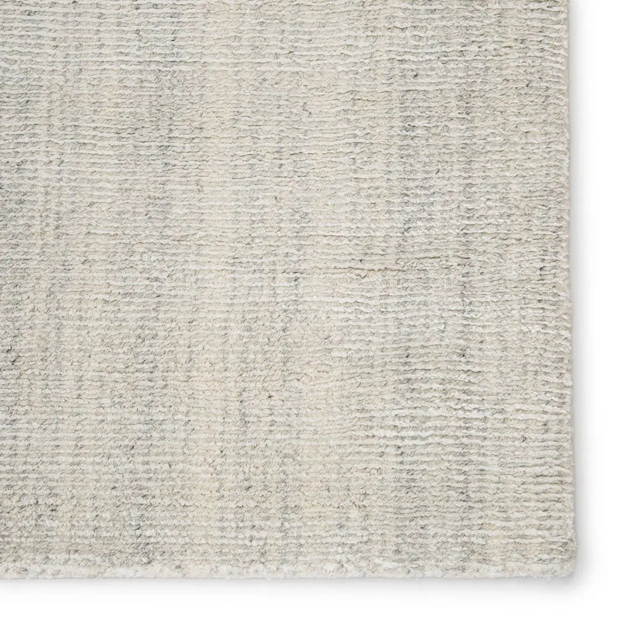 An ivory-colored area rug with a textured weave, partially showing its thickness and material.