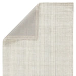 An ivory-colored area rug with a textured weave, partially showing its thickness and material.
