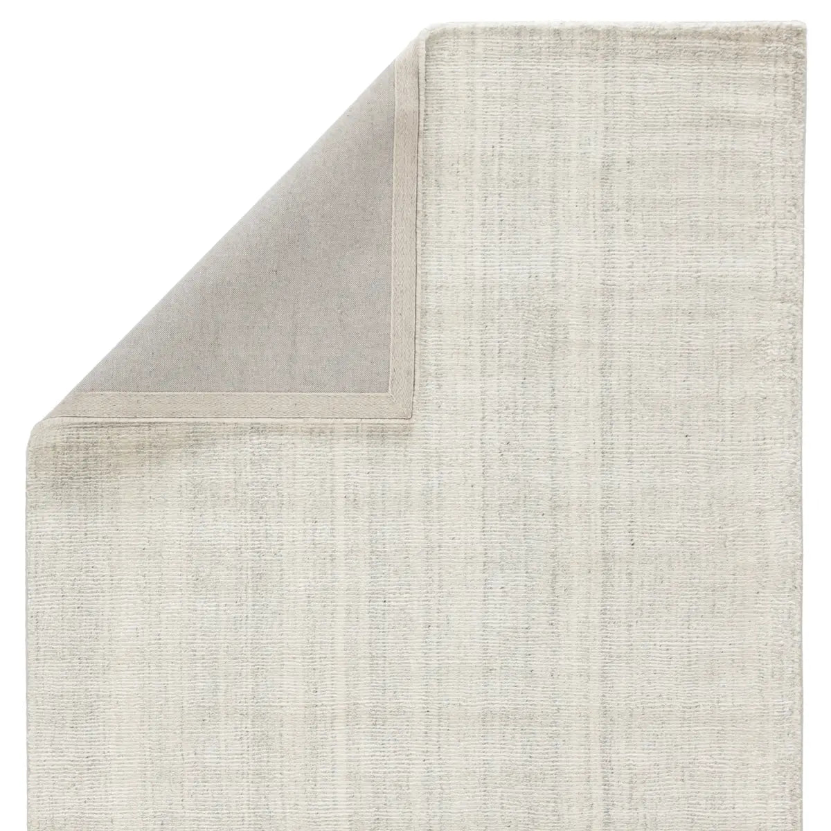 An ivory-colored area rug with a textured weave, partially showing its thickness and material.