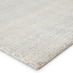 An ivory-colored area rug with a textured weave, partially showing its thickness and material.