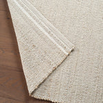 Close-up of a textured beige rug on a wooden floor