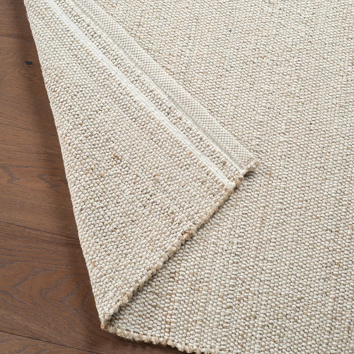 Close-up of a textured beige rug on a wooden floor