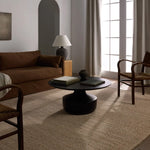 Modern living room with a brown sofa, black coffee table, and wooden chairs.