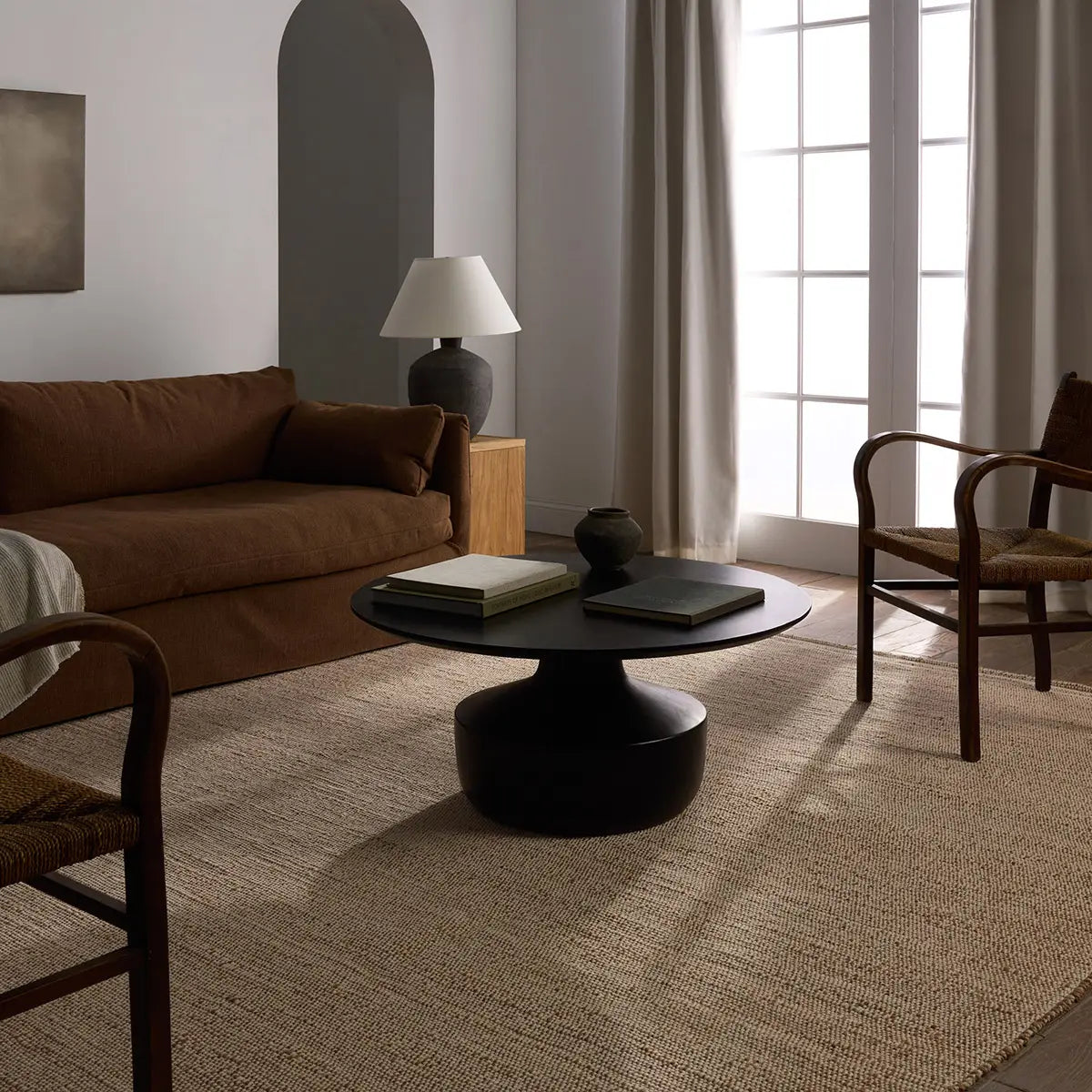 Modern living room with a brown sofa, black coffee table, and wooden chairs.