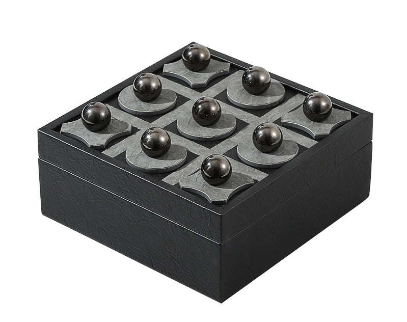 A leather tic tac toe game with a black box and a grid pattern on the board for marking moves.