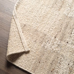 Close-up of a textured beige rug on a wooden floor