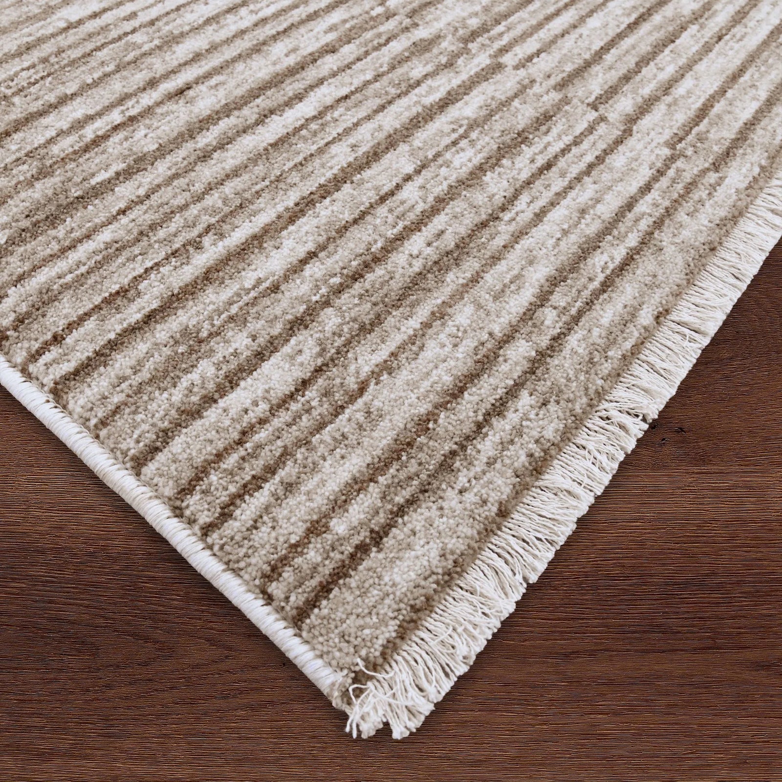 Beige textured rug with fringes on a wooden floor
